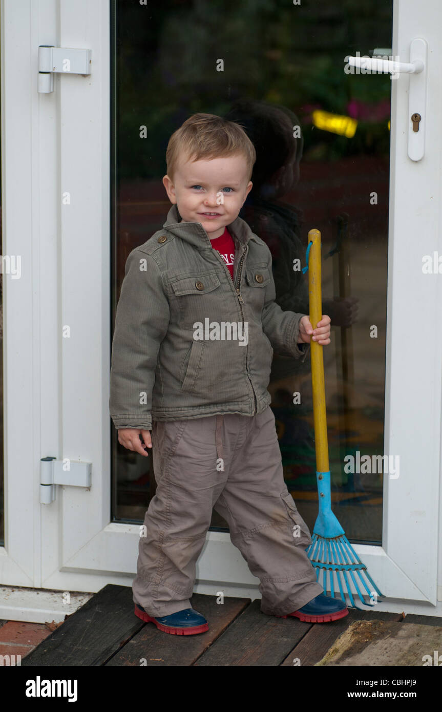 Small boy holding rake Stock Photo - Alamy