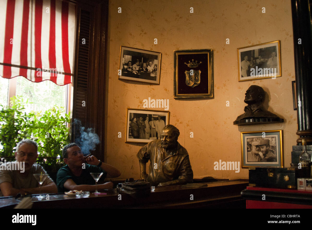 Statue of Ernest Hemingway at the bar of El Floridita  and two tourists smoking a cigar. Havana, Cuba Stock Photo