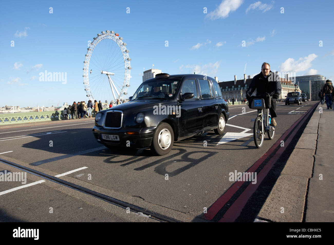 man on hired cycle being overtaken by black london cab taxi on westminster bridge in central london england united kingdom uk Stock Photo