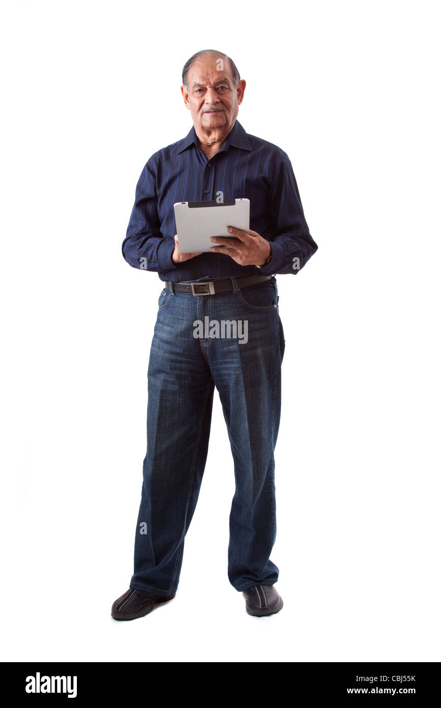Portrait of a smiling elderly East Indian businessman using an iPad digital tablet Stock Photo