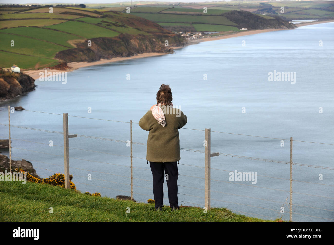 Woman standing by cliff top safety fence at Start Point in Devon England Uk Stock Photo