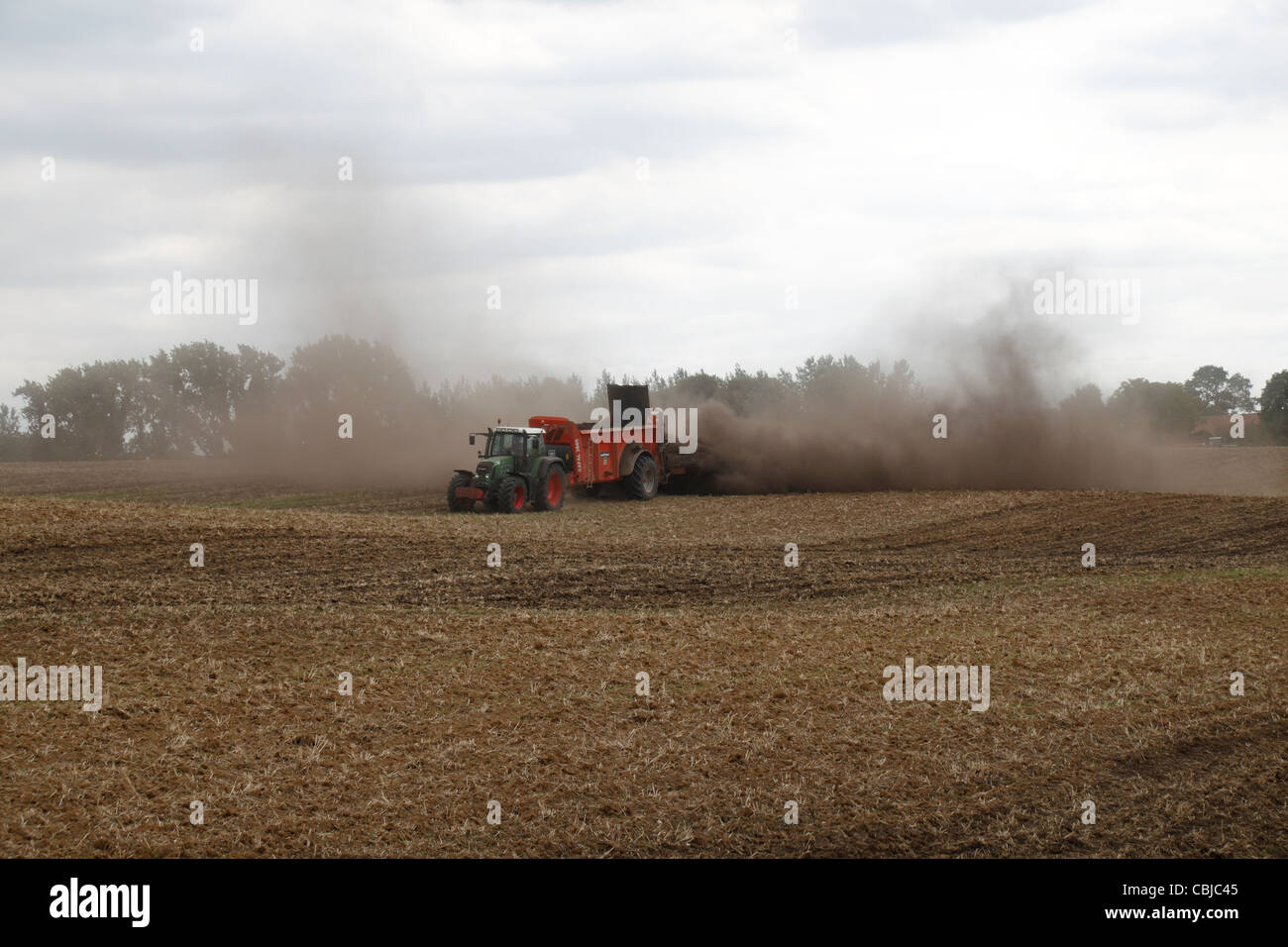 Tractor with Sodimac manure spreader (epandeur de fumier) spreading manure on an uncultivated field in northern France. Stock Photo