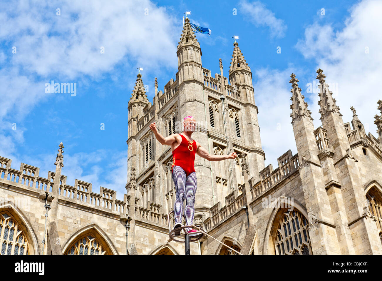 High wire street performer performing in front of the Bath Abbey, Bath Spa, England. Stock Photo
