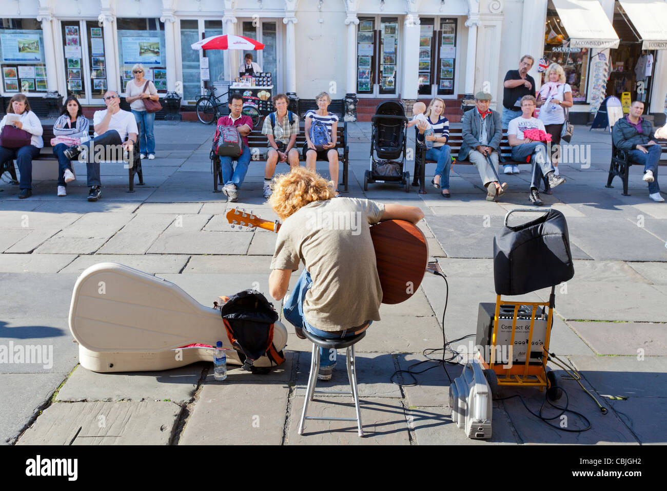 Street musician performer playing his guitar in front of a crowd of people at the Bath Abbey, Bath Spa, England. Stock Photo