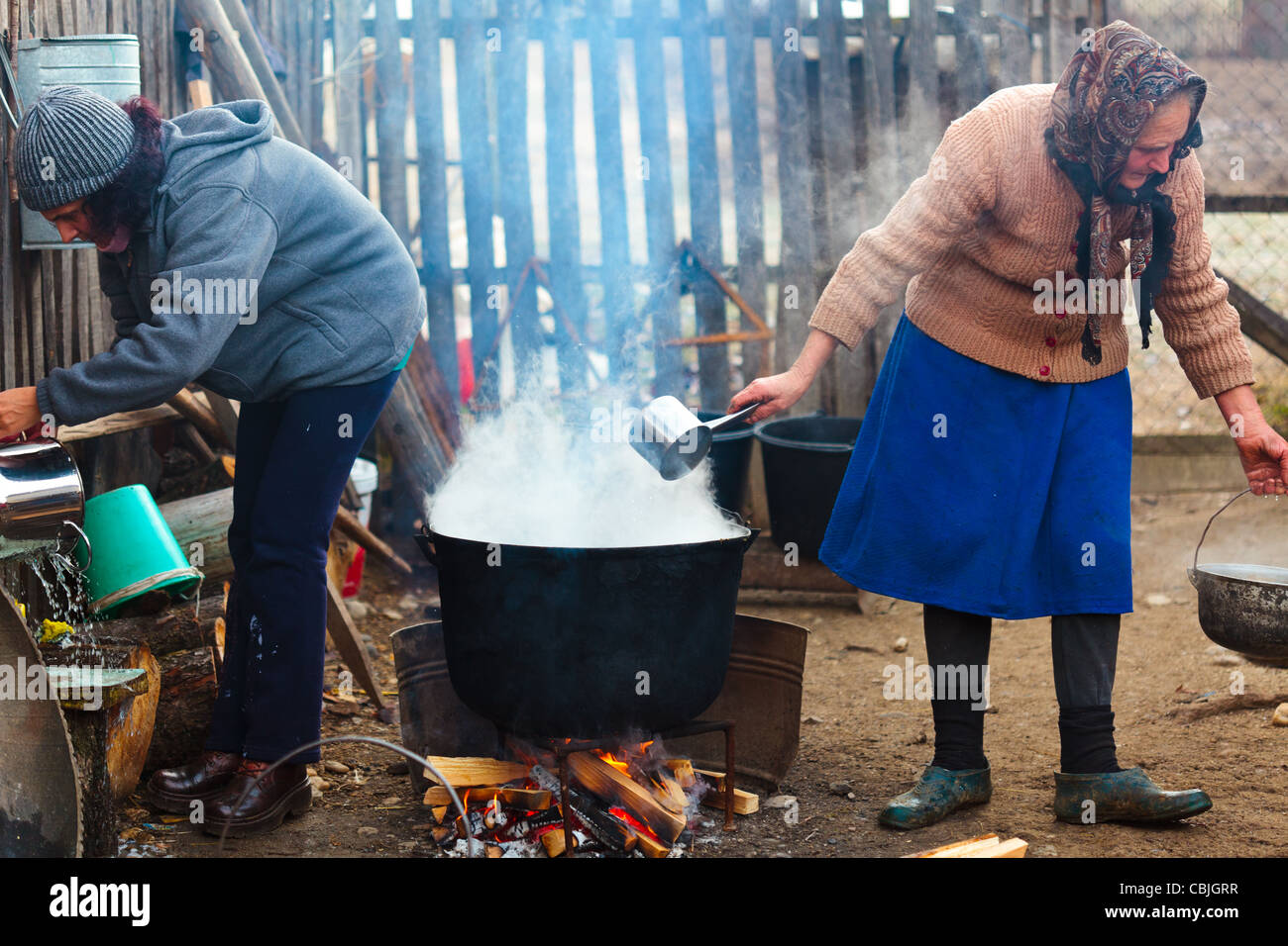Women near castiron pot boiling water outdoor in the countryside Stock