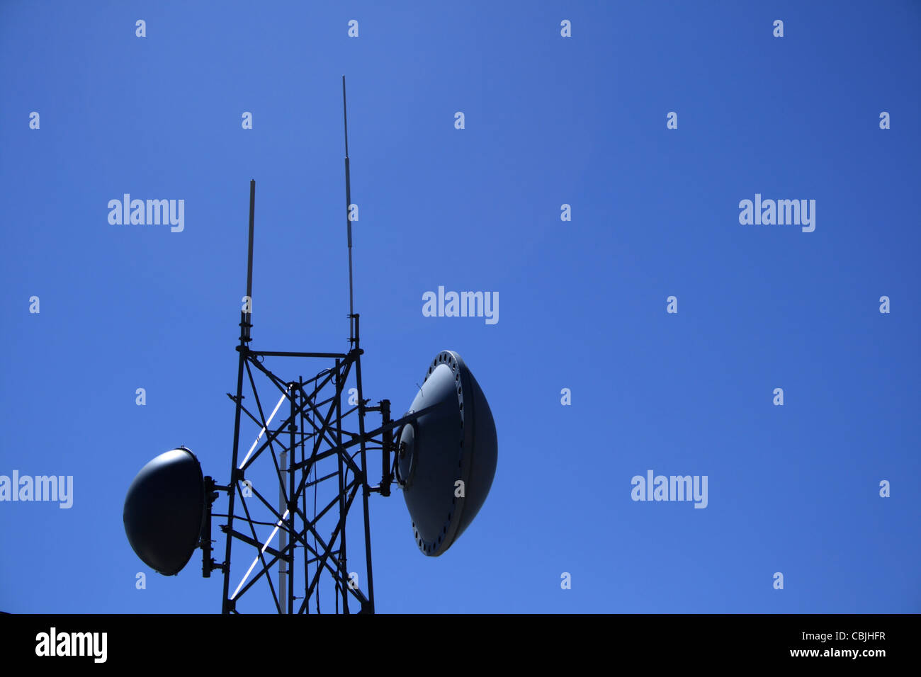 microwave antenna tower with blue sky copy space to the side Stock Photo