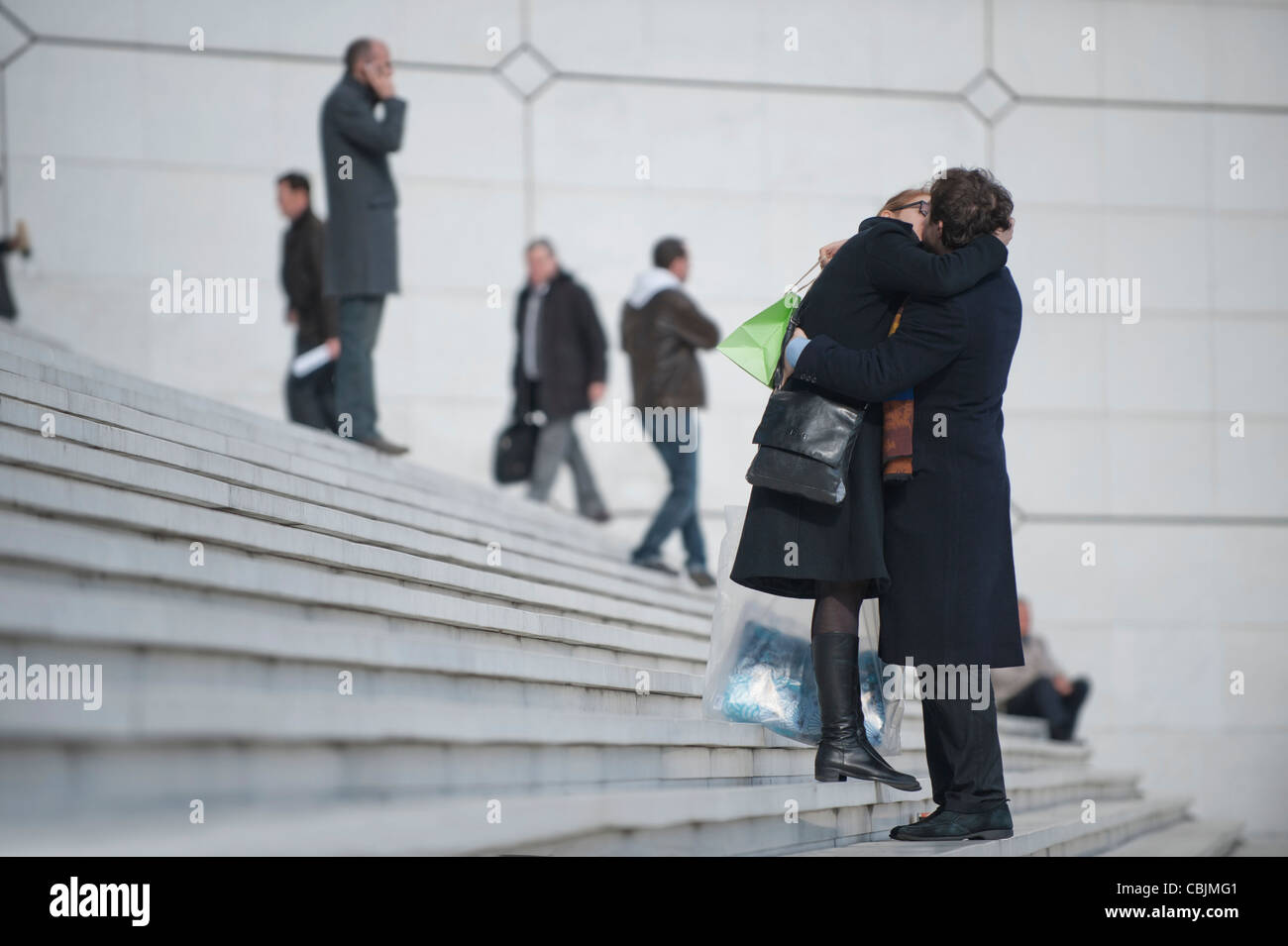 A young French couple kiss on the steps of Grande Arche of La Défense in Paris, France. Stock Photo