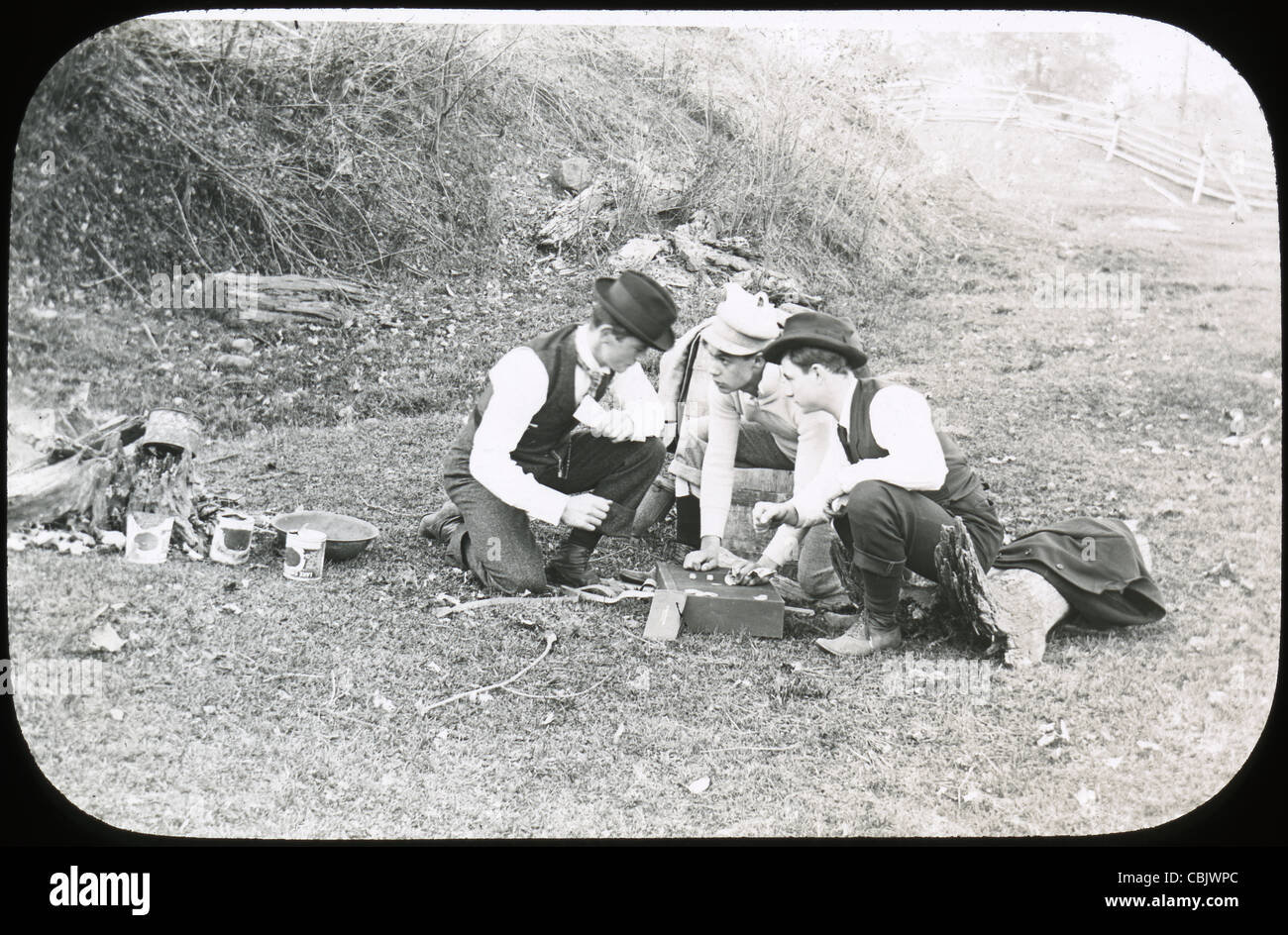 Circa 1910s antique photograph of three men wagering on some sort of dice game. Stock Photo