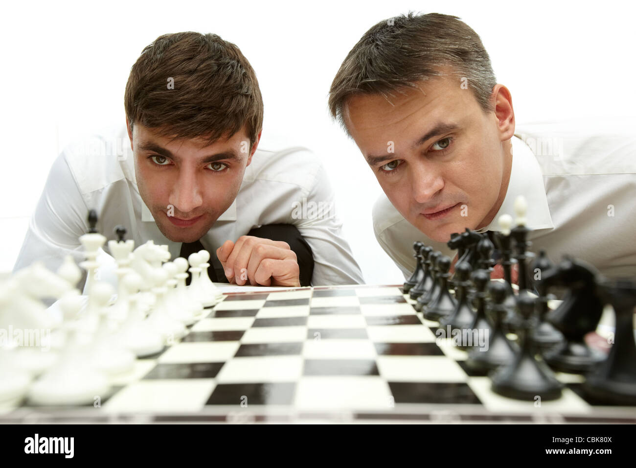 Two men looking at chess figures on chess board Stock Photo