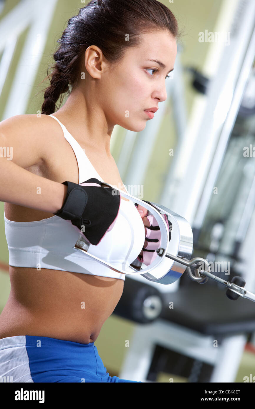 Photo of active girl pumping muscles on special equipment Stock Photo