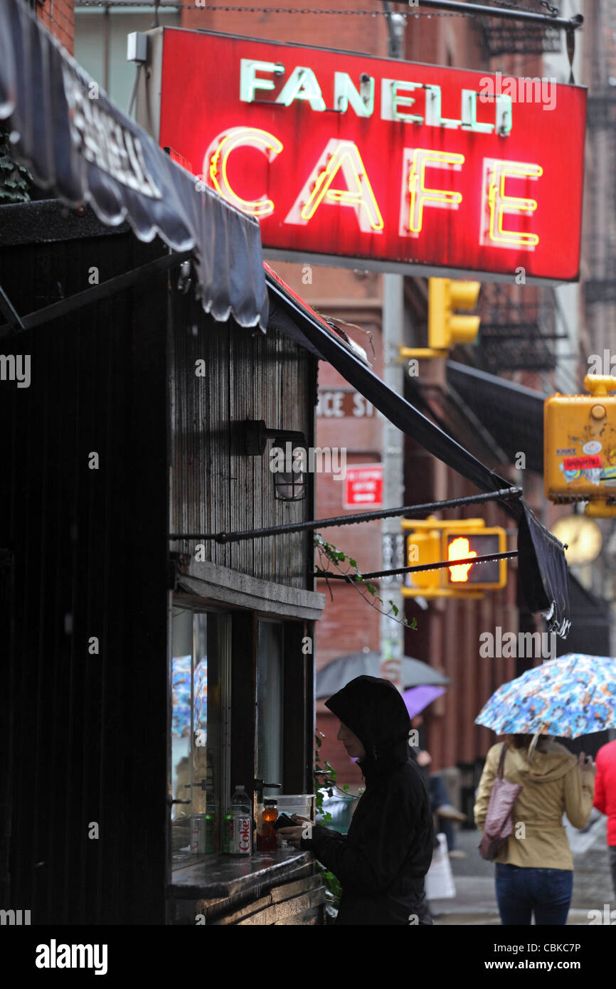 woman buying takeaway food under, illuminated neon sign 'Fanelli Cafe', SoHo, Manhattan, New York City, NYC, USA Stock Photo