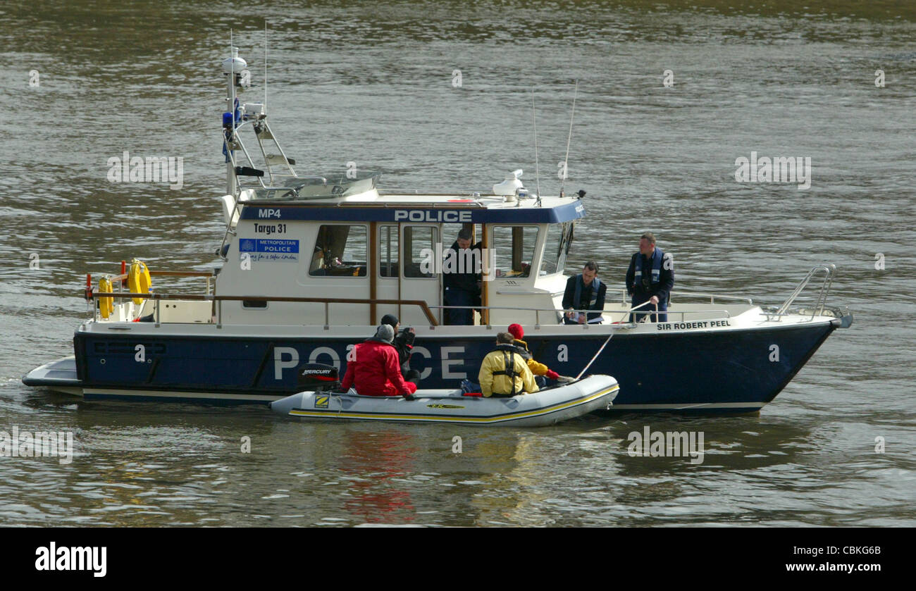 Metropolitan Police launch stops a dinghy on the river Thames by the Houses of Parliament in London. Stock Photo