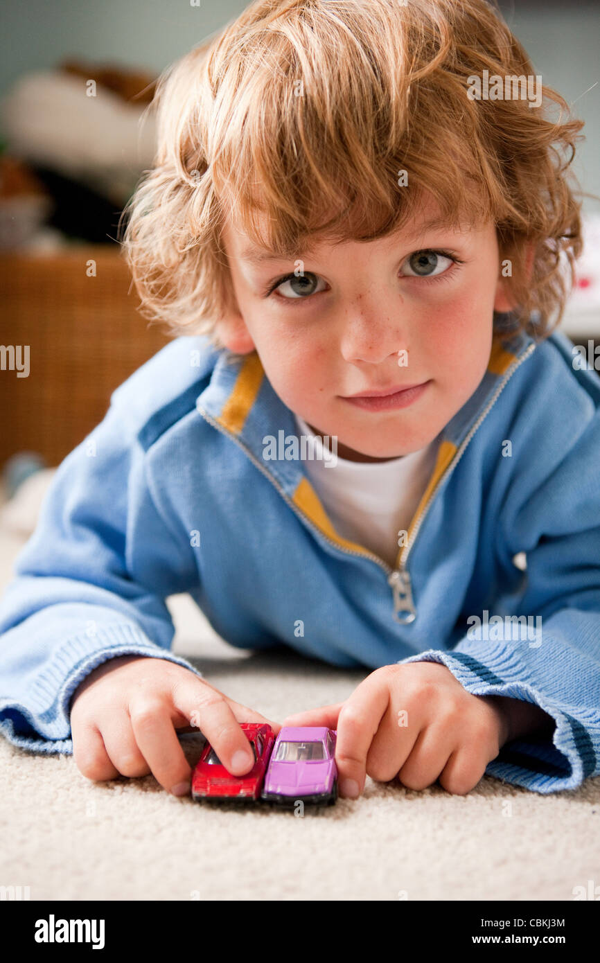Young boy playing at home with two toy cars Stock Photo - Alamy