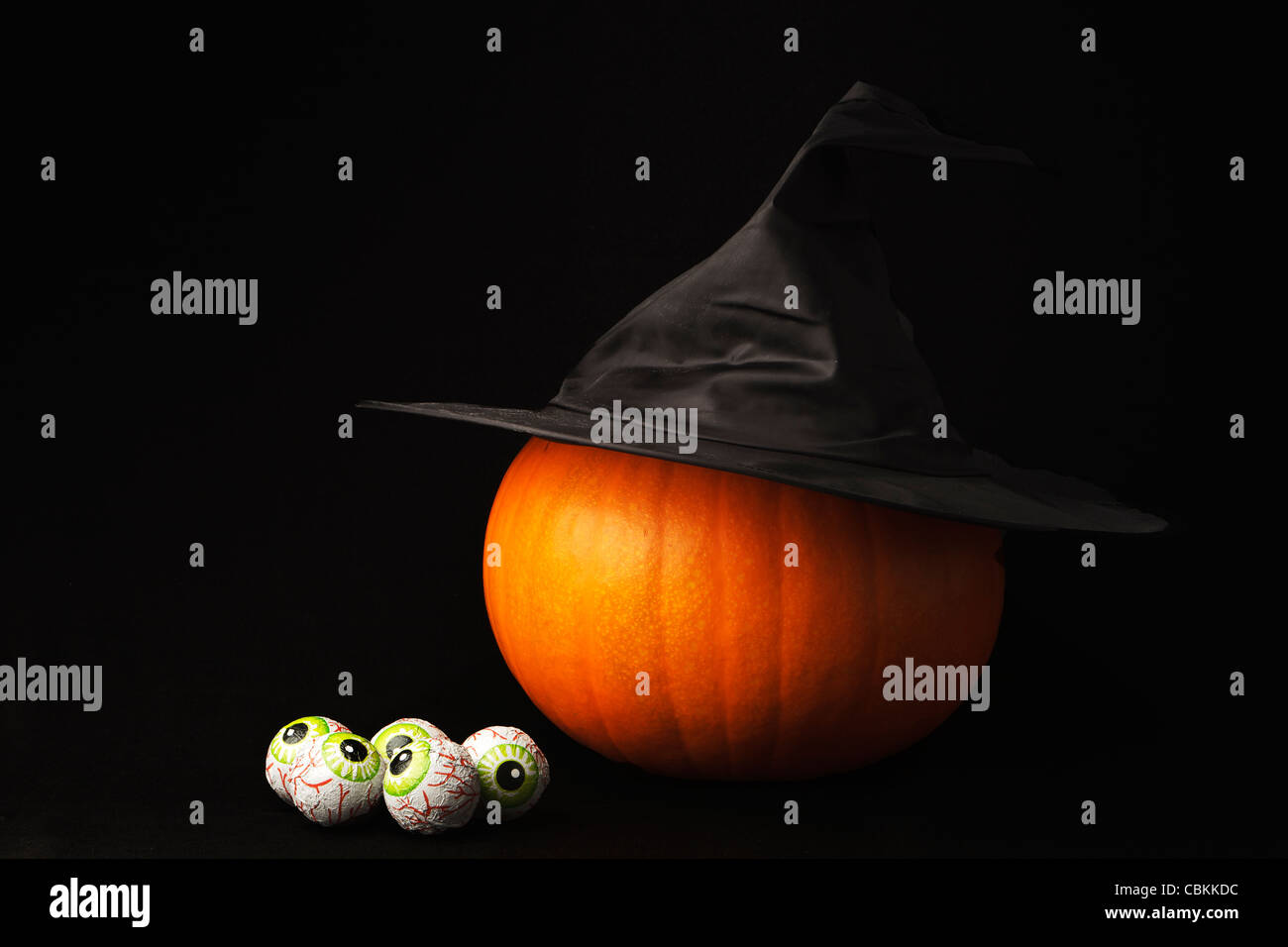 Making a witches halloween lantern - pumpkin, witches hat, eyeballs, black background Stock Photo