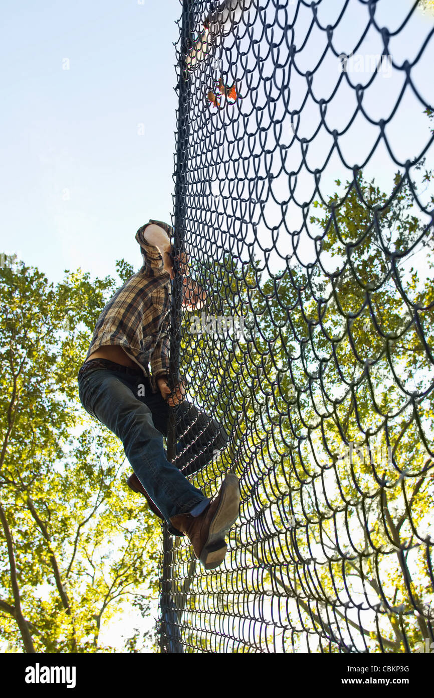 Mid adult man climbing over chain link fence Stock Photo Alamy