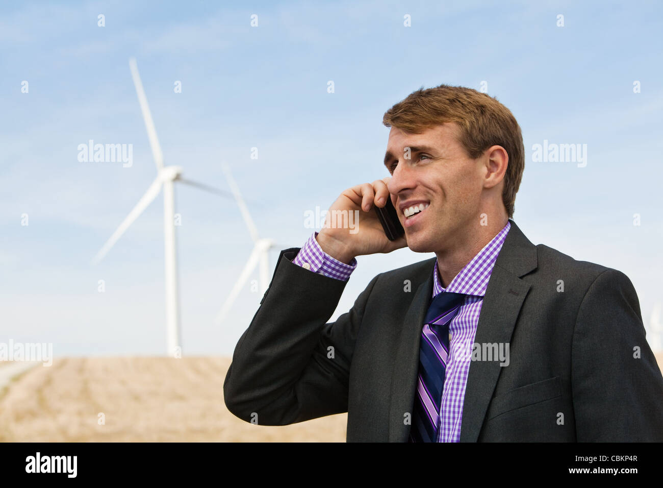 Man on mobile phone in front of wind turbines Stock Photo