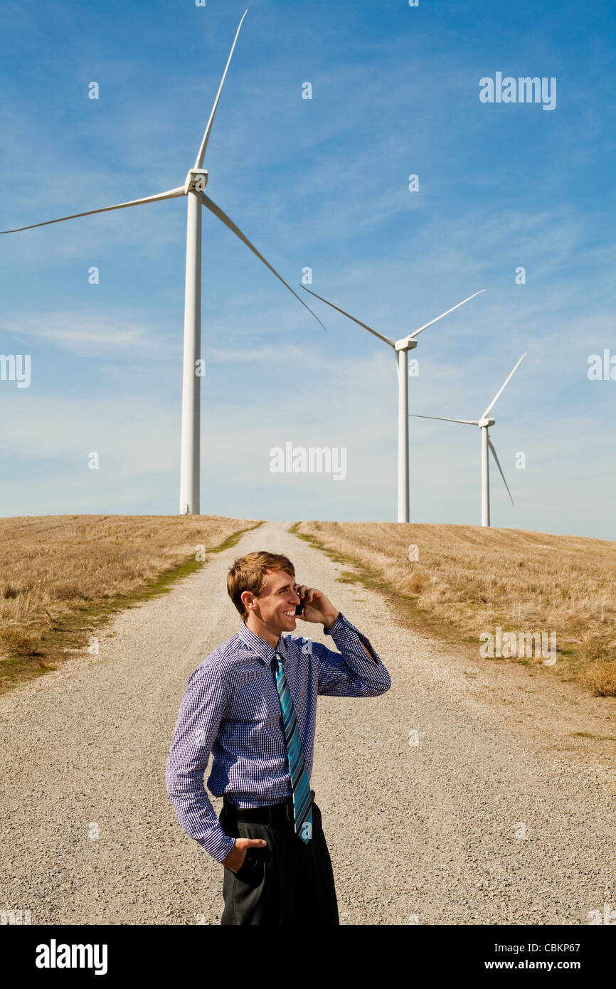 Man using mobile phone in front of wind turbines Stock Photo