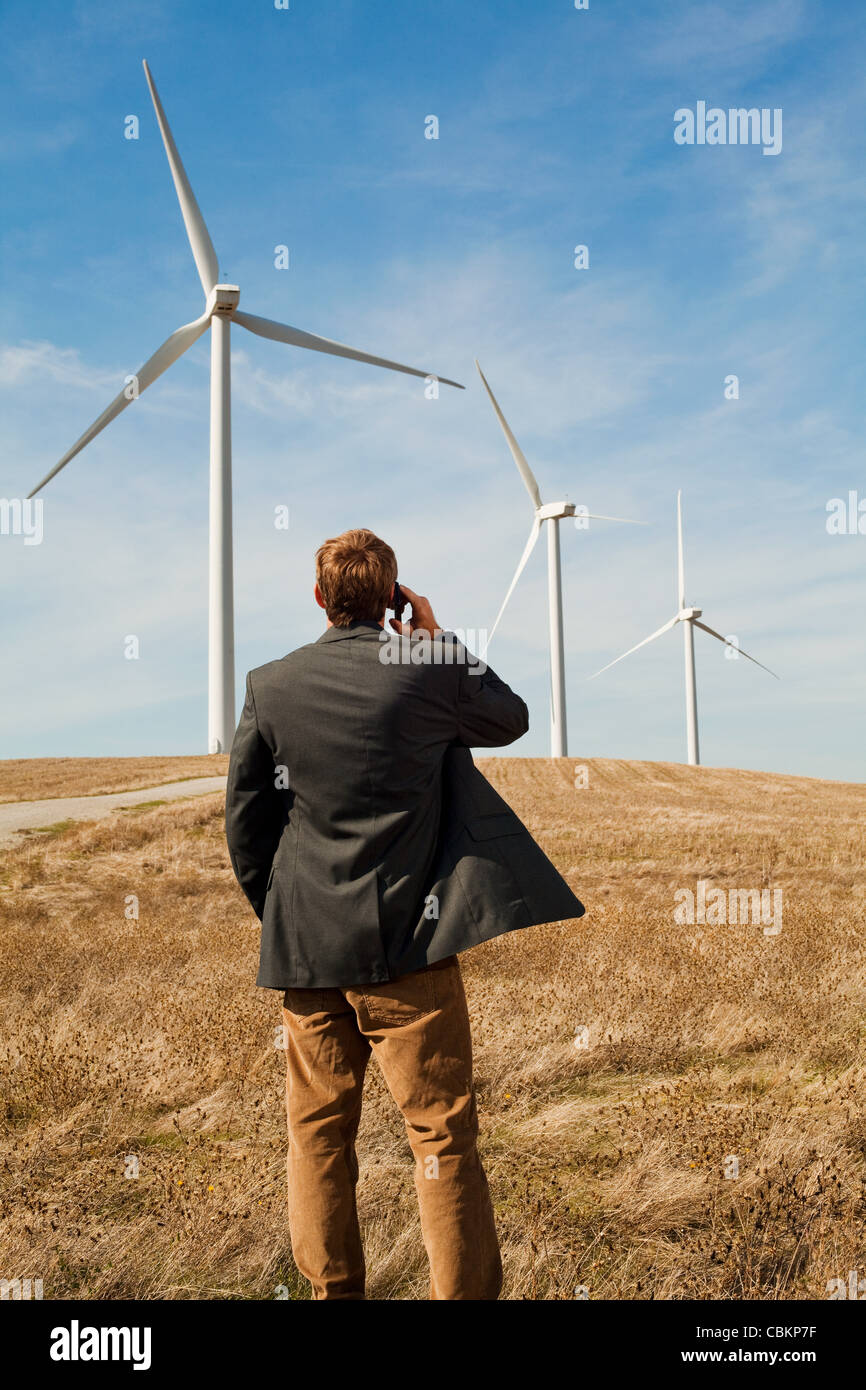 Man standing in front of wind turbines on mobile phone Stock Photo