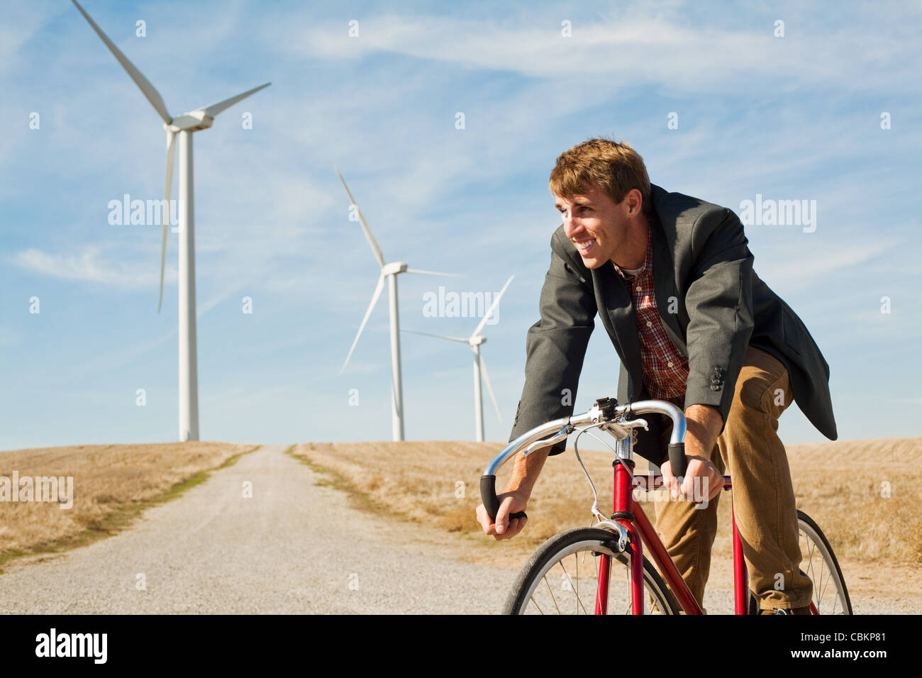 Man on bicycle in front of wind turbines Stock Photo