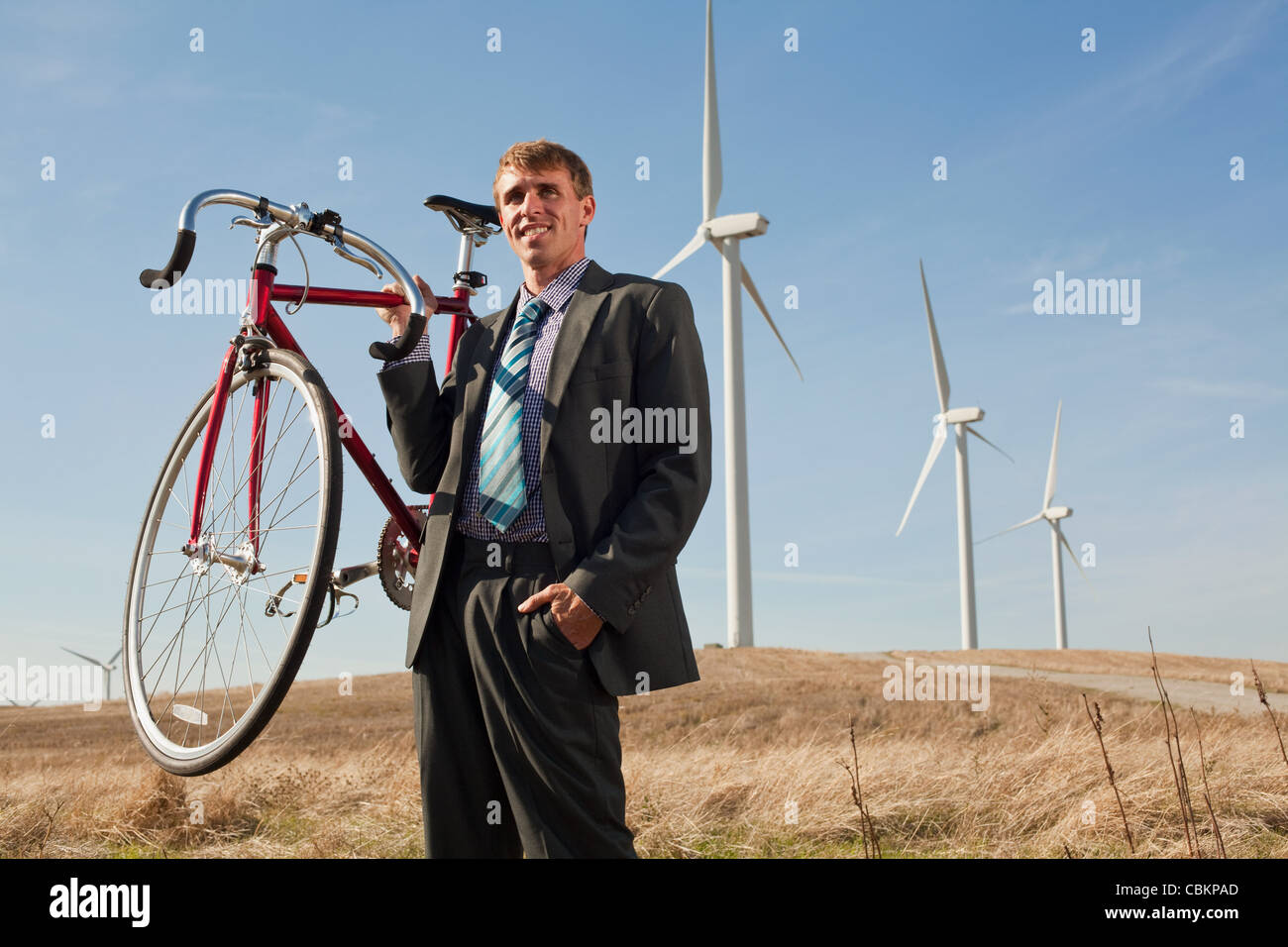 Man holding bicycle in front of wind turbines Stock Photo