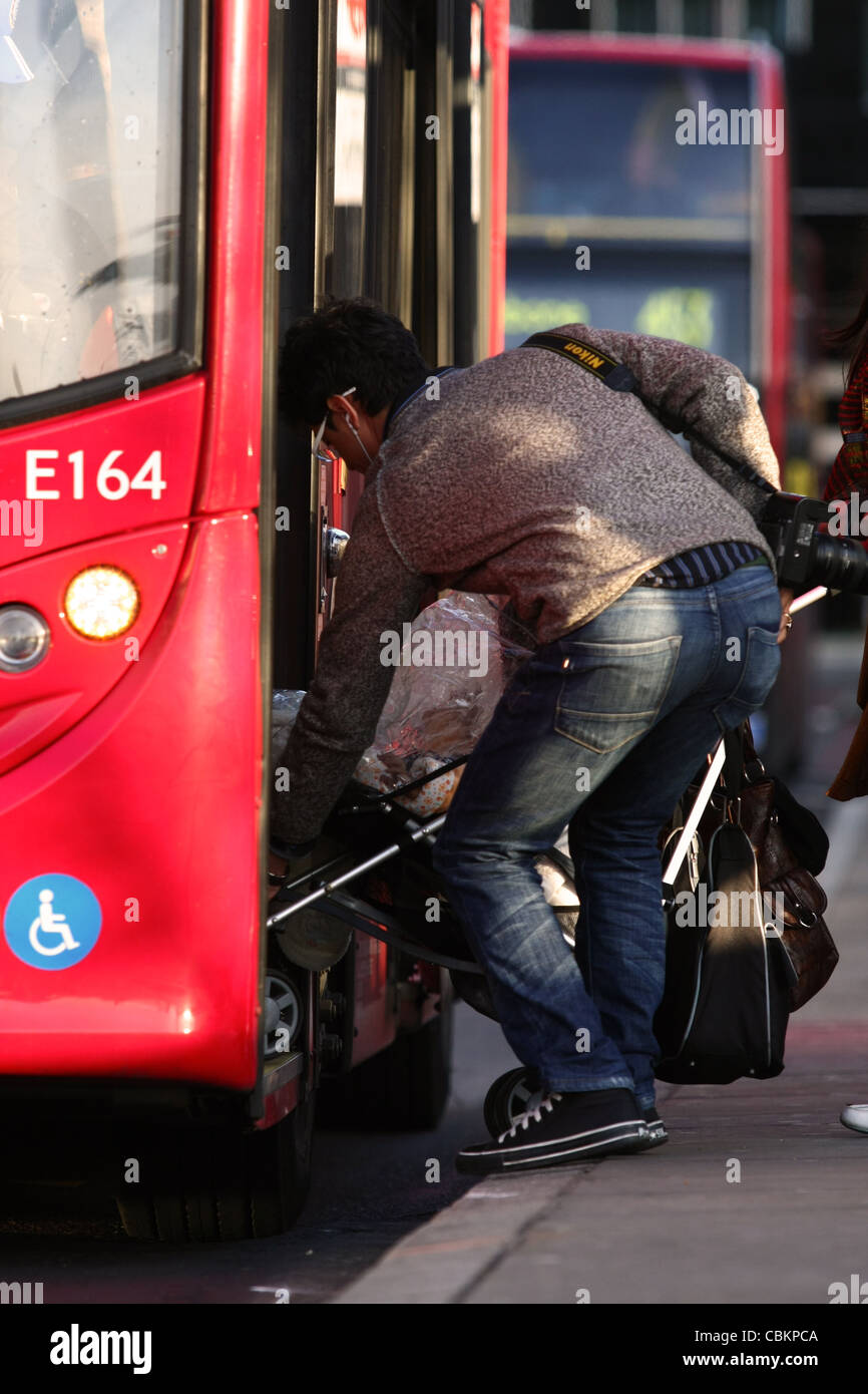 two people struggling to board a red London bus with a pushchair Stock Photo