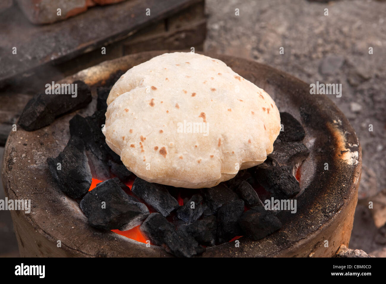 India, West Bengal, Kolkata, Esplanade, cooking, roti being puffed up in fire coals at bus station food stall Stock Photo