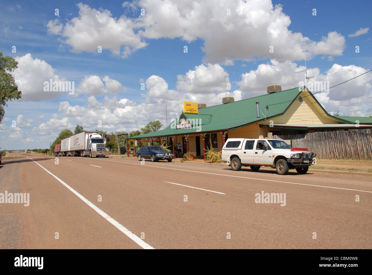 The roadside pub Wellshot Hotel off the highway in Ilracombe, Outback Queensland, Australias, with cars and roadtrain parked Stock Photo