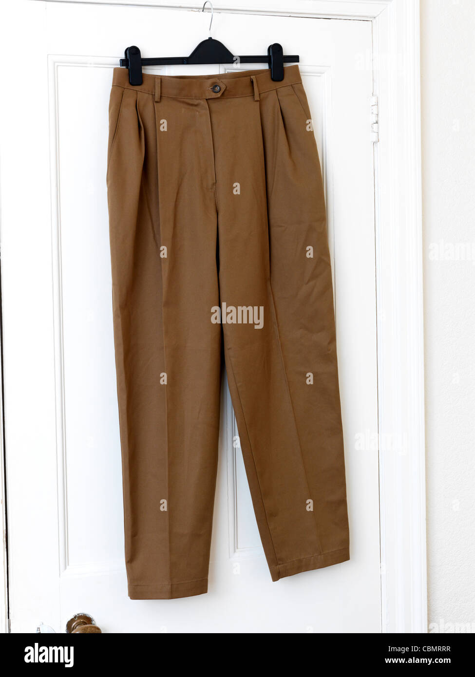 Brown Trousers Hanging On The Back Of A Door Stock Photo