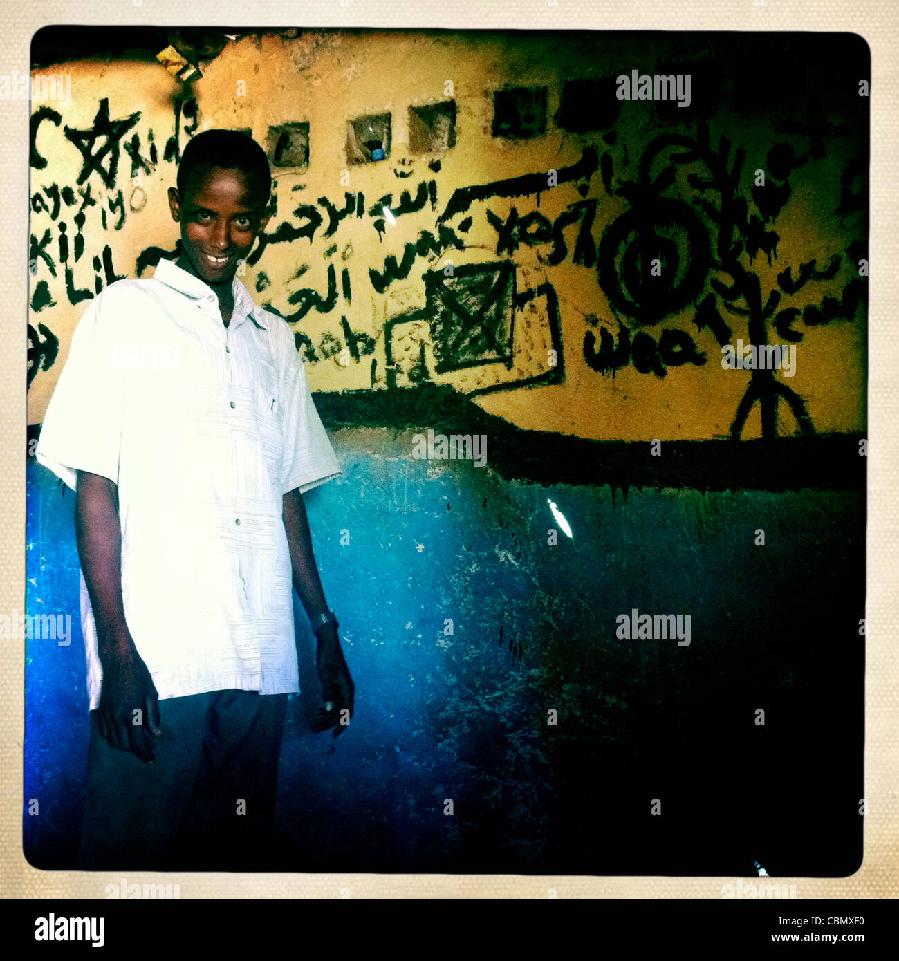 Teenage Boy Standing Near Arabic Graffiti Painted Wall In Somaliland Stock Photo