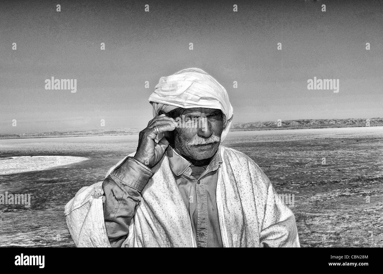 Arab man on cell phone Great Dry Salt Lake Chott el Jerid in Sahara Desert sand near Douz in Tunisia isolated Africa Stock Photo