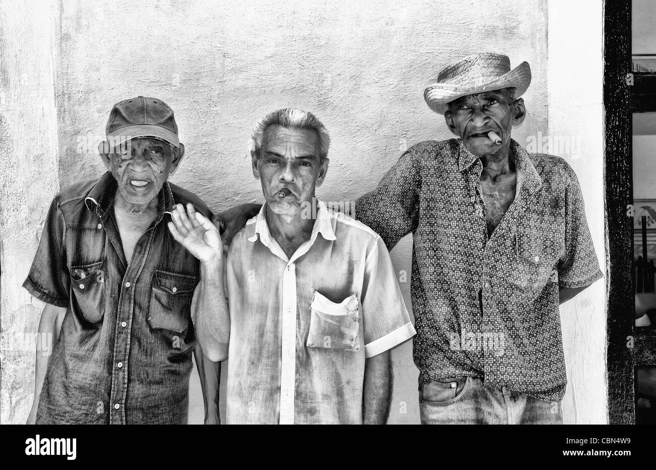 Local old men with cigar against bright yellow wall of building of the old colonial city of Trinidad in Cuba Stock Photo