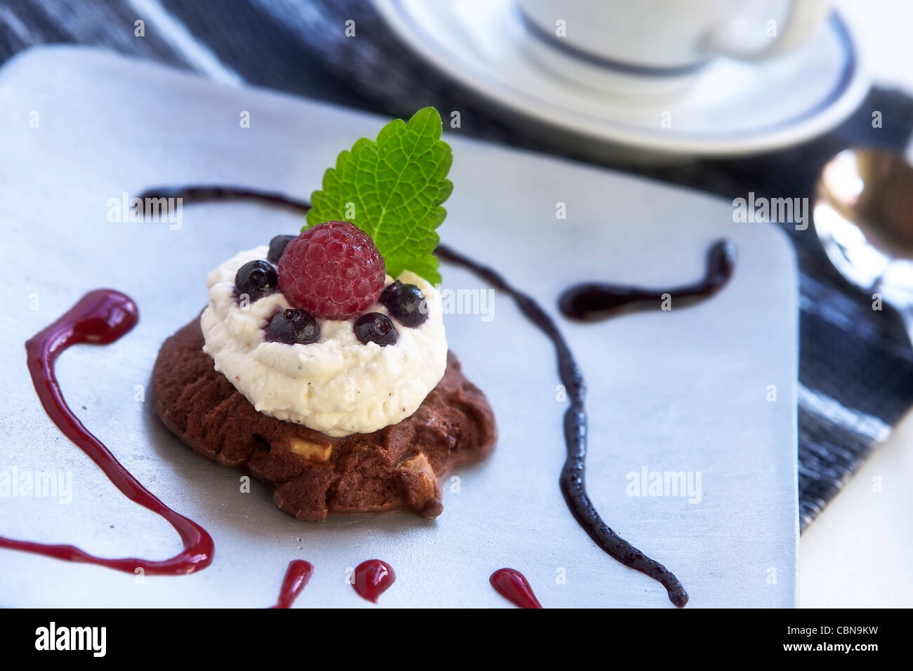 Chocolate chip cookie, topped with a marsala mascarpone cream and berries, served with lemon and fruit sauce Stock Photo