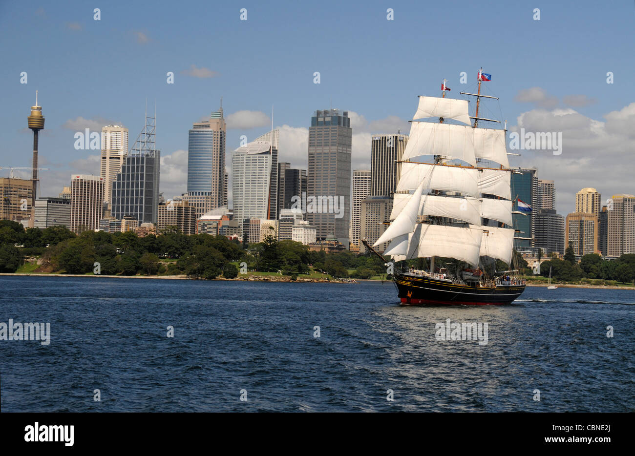 The three-mast clipper, Stad Amsterdam, built in Amsterdam in the Netherlands in 2,000, makes her way along  Sydney bay towards the open sea after her Stock Photo