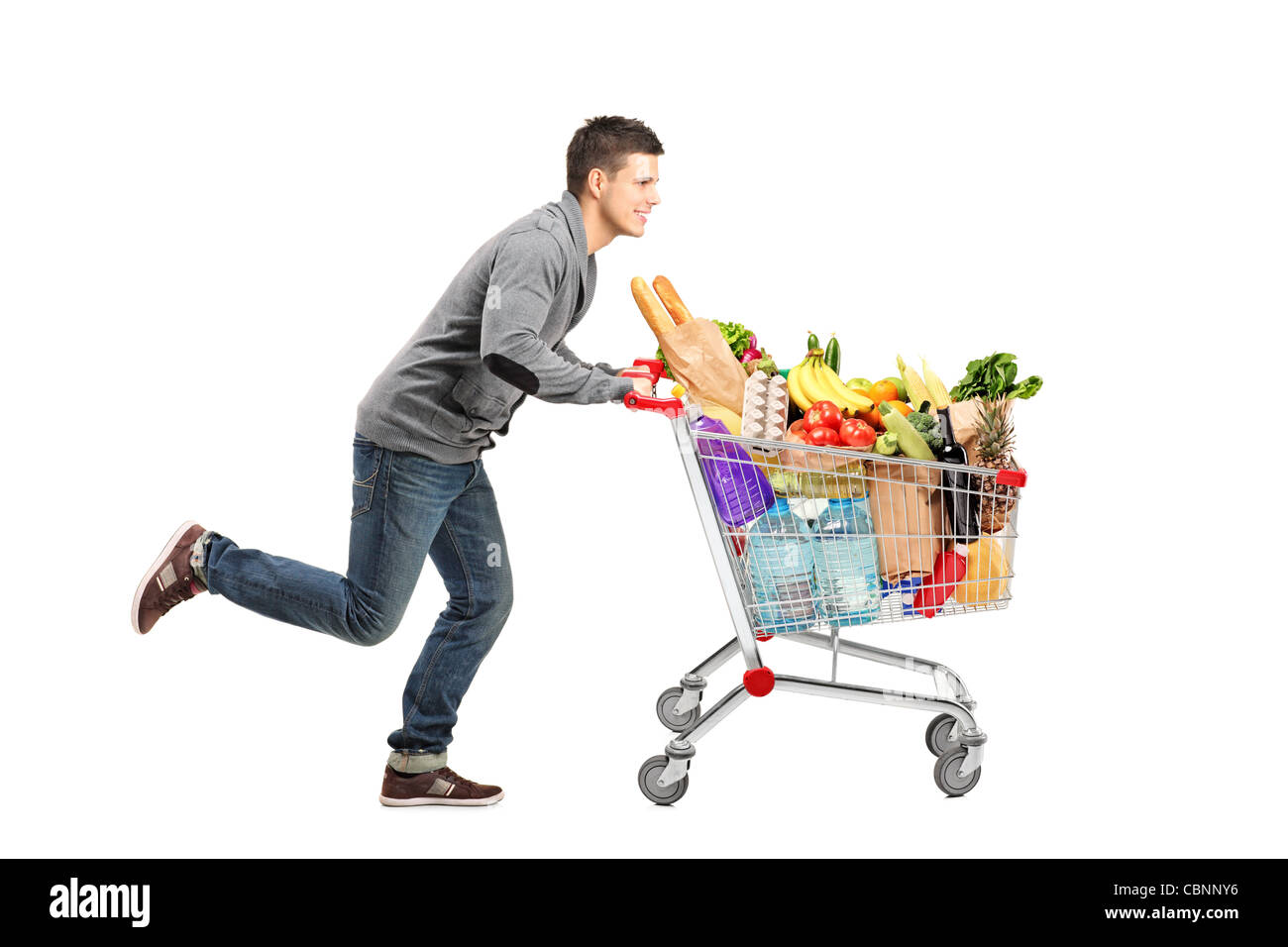 Young man running and pushing a shopping cart full with food Stock Photo Alamy