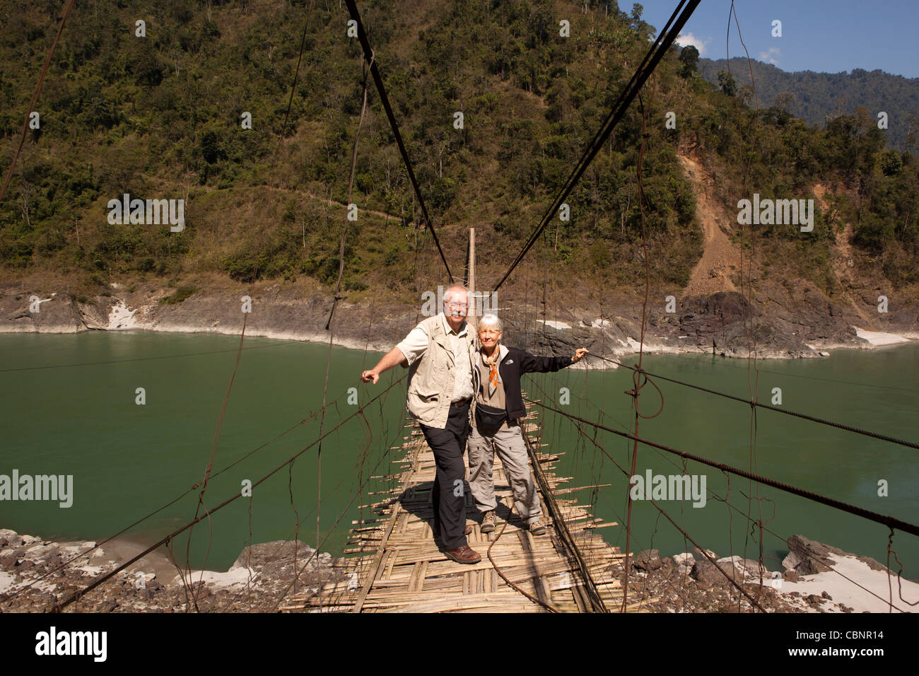India, Arunachal Pradesh, Kabang, Himalayan foothills, western couple crossing suspension bridge over Siang River Stock Photo