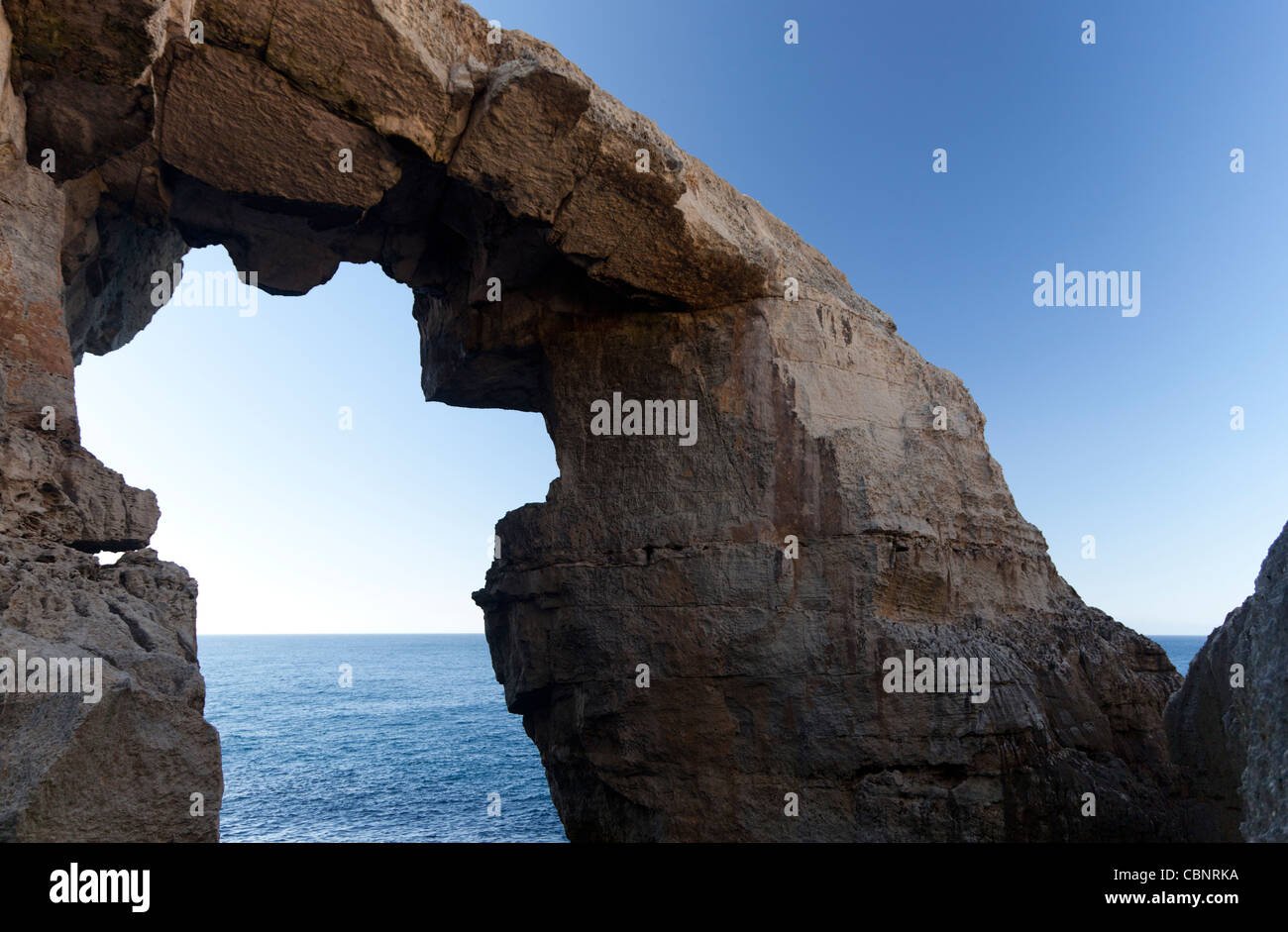 A natural and dramatic rocky arch at the point where Mielah Valley reaches the sea in Gharb in west Gozo. Stock Photo