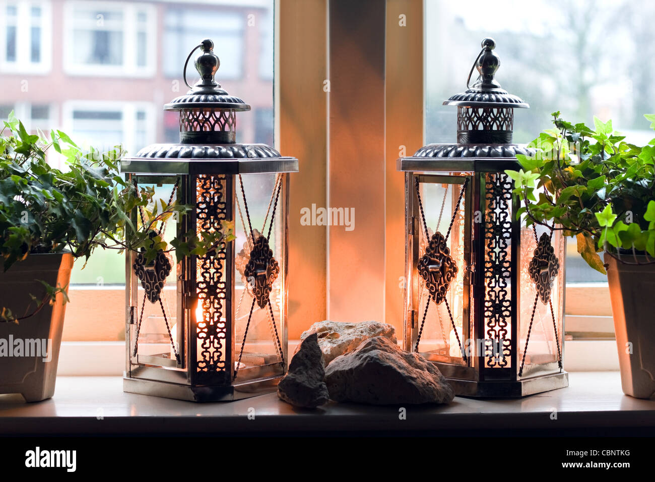 Lanterns with burning candles in window on rainy winterday - homelike inside, cold outside Stock Photo
