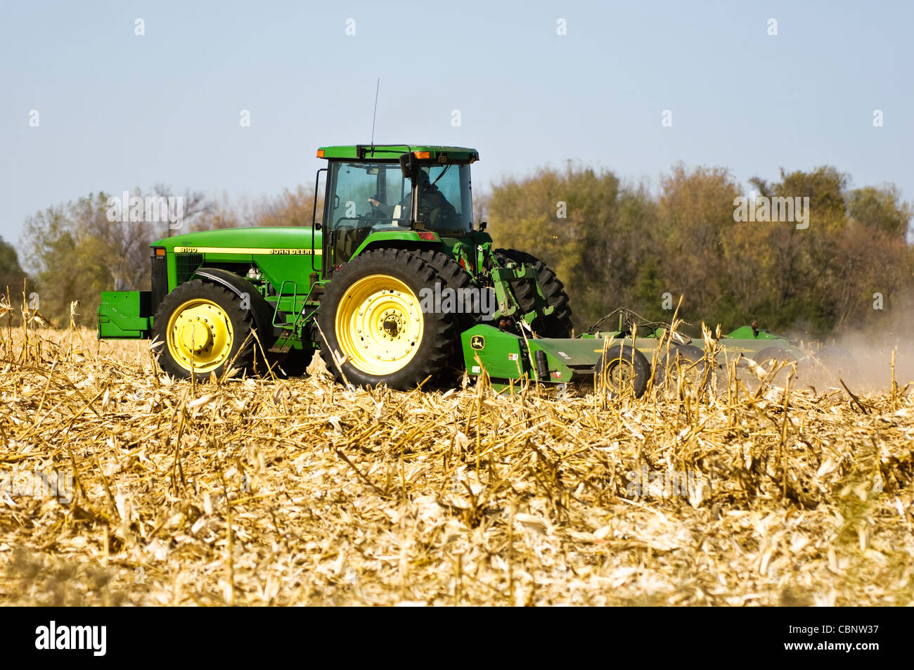 A tractor pulls a stalk chopper to cut down corn stalks prior to