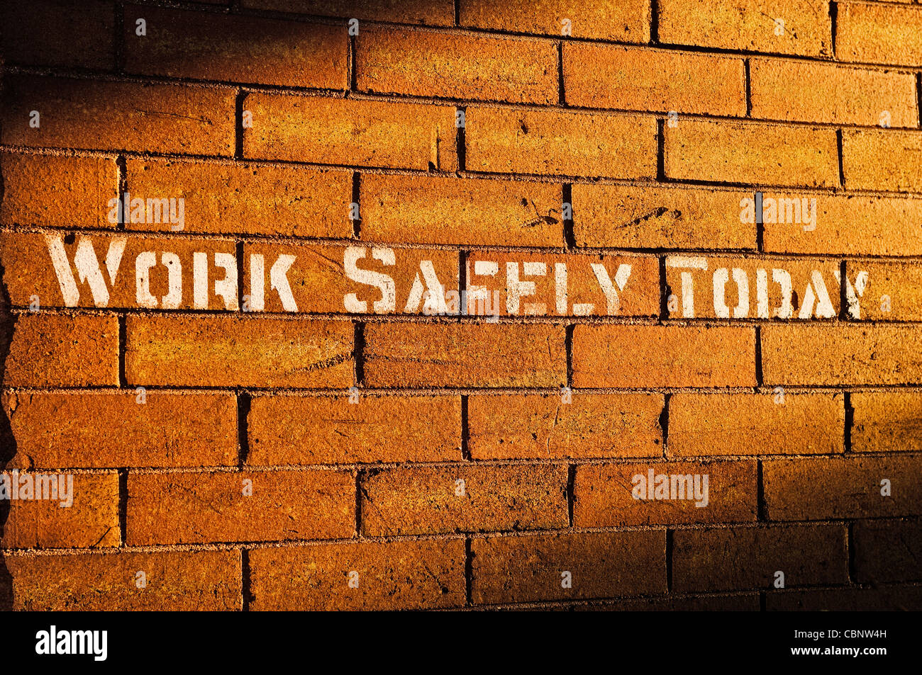 Words stenciled on brick wall reading 'Work Safely Today' Stock Photo