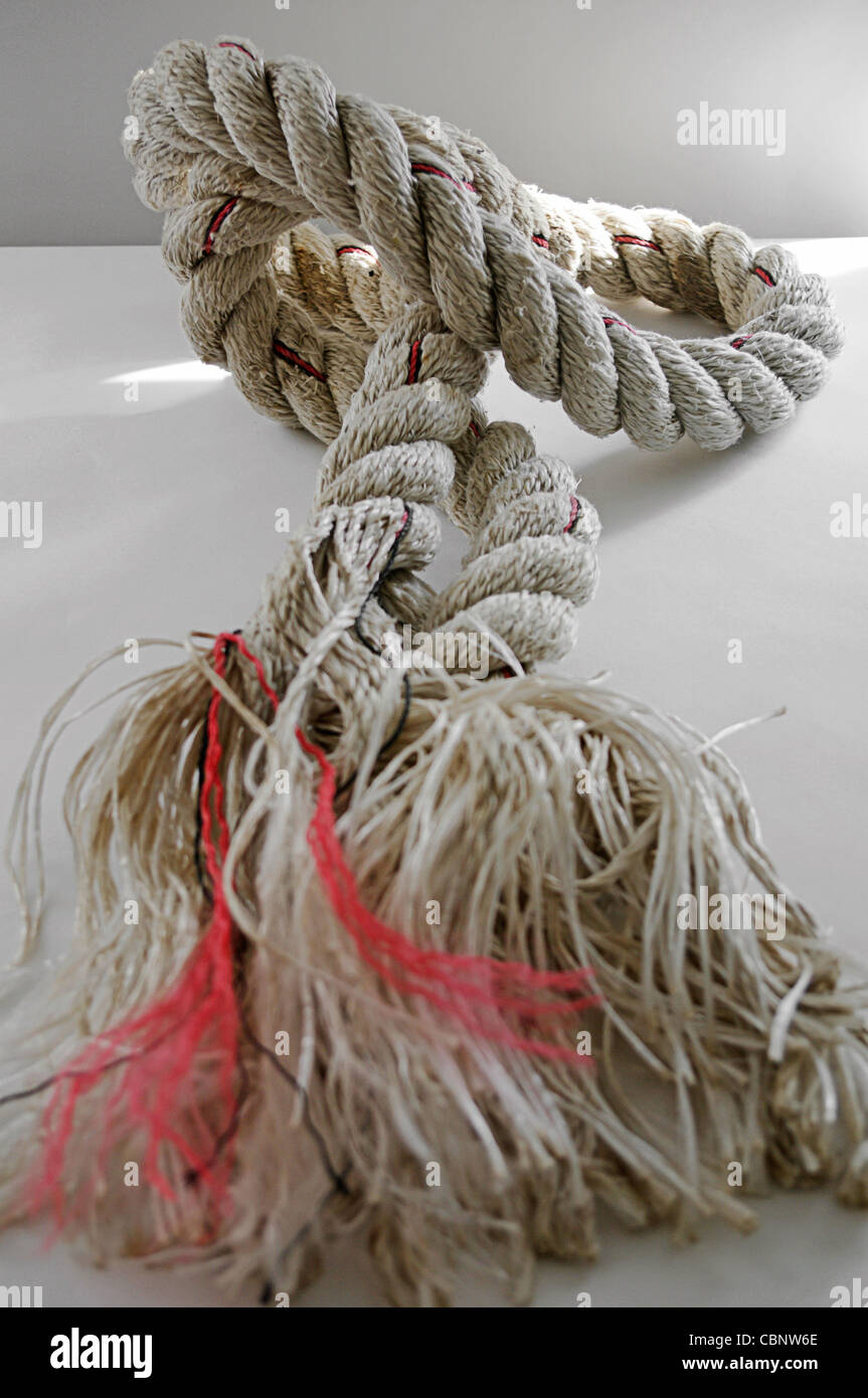 Neatly twisted multi-ply rope coming apart into a disorganized tangle of loose ends Stock Photo