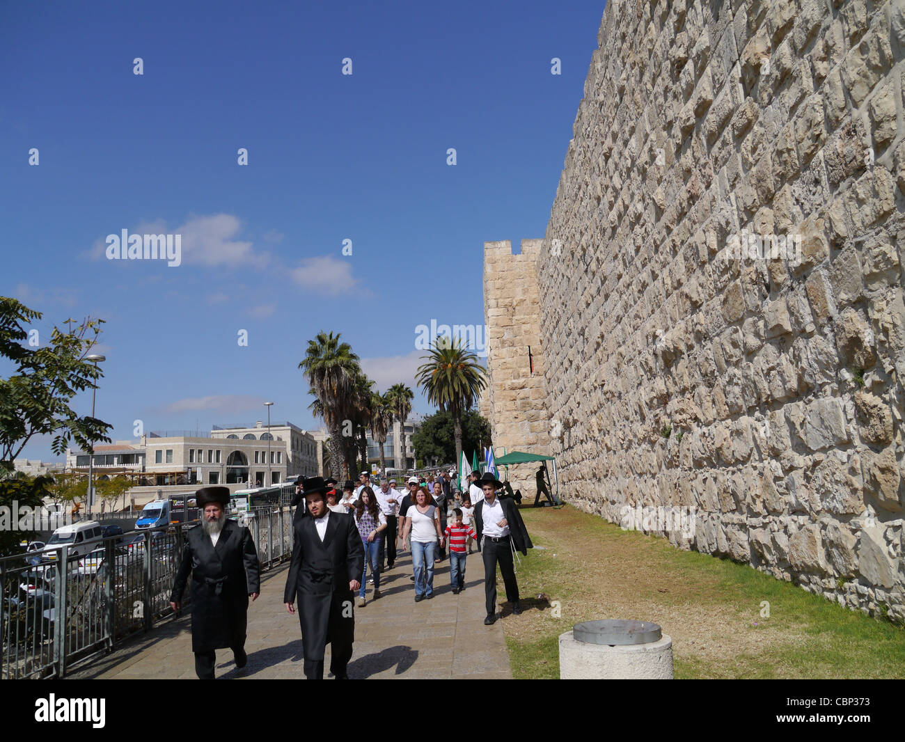 Religious Jews walking beside exterior walls of the Old City of Jerusalem near Jaffa Gate Stock Photo