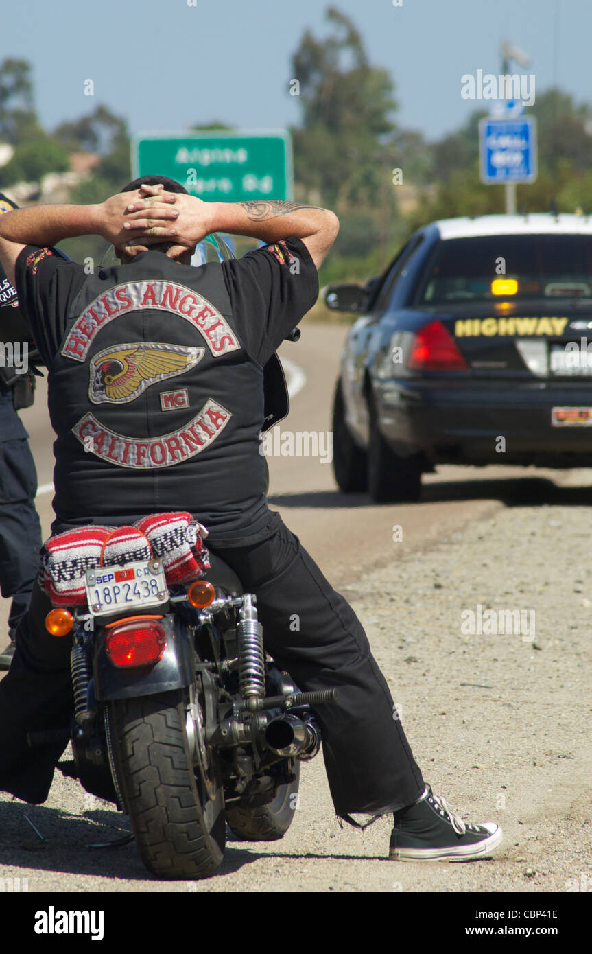 A member of the Hell's Angels keeps his hands behind his head during a traffic stop. Stock Photo