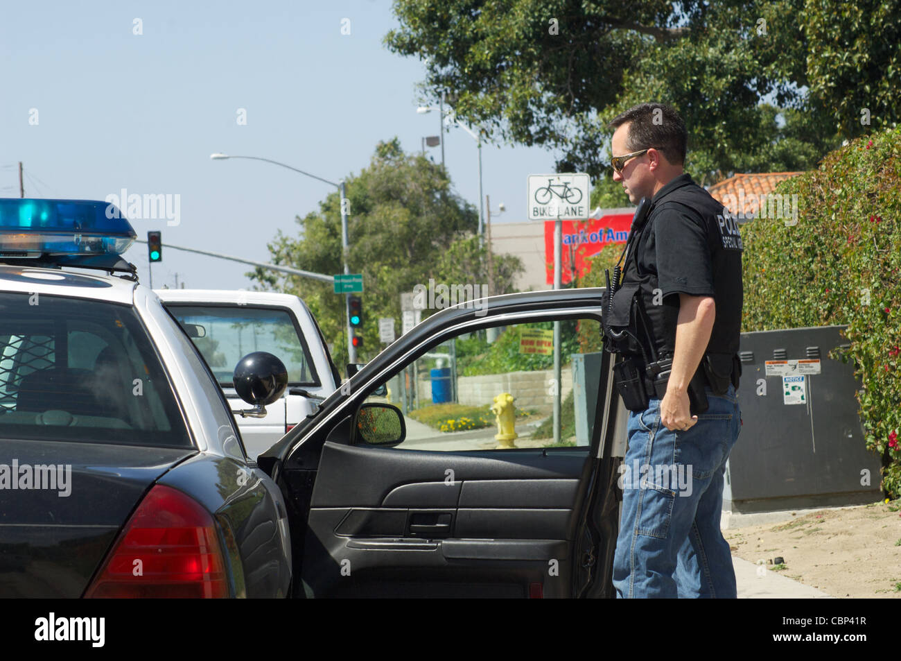 A police officer in blue jeans and tactical gear on a traffic stop ...