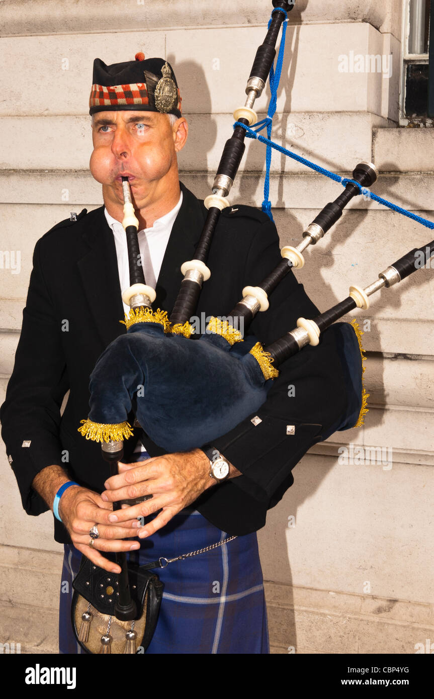 A busker playing the bagpipes with his cheeks full of air in Norwich , Norfolk , England , Britain , Uk Stock Photo