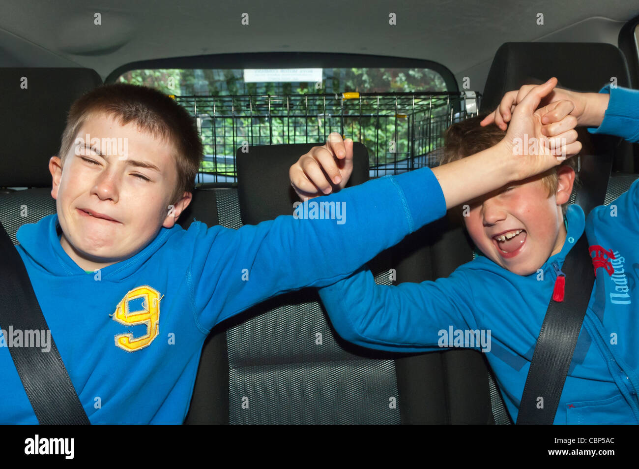 Two brothers boys children fighting in the car showing the difficulty of driving with kids on board in the Uk Stock Photo