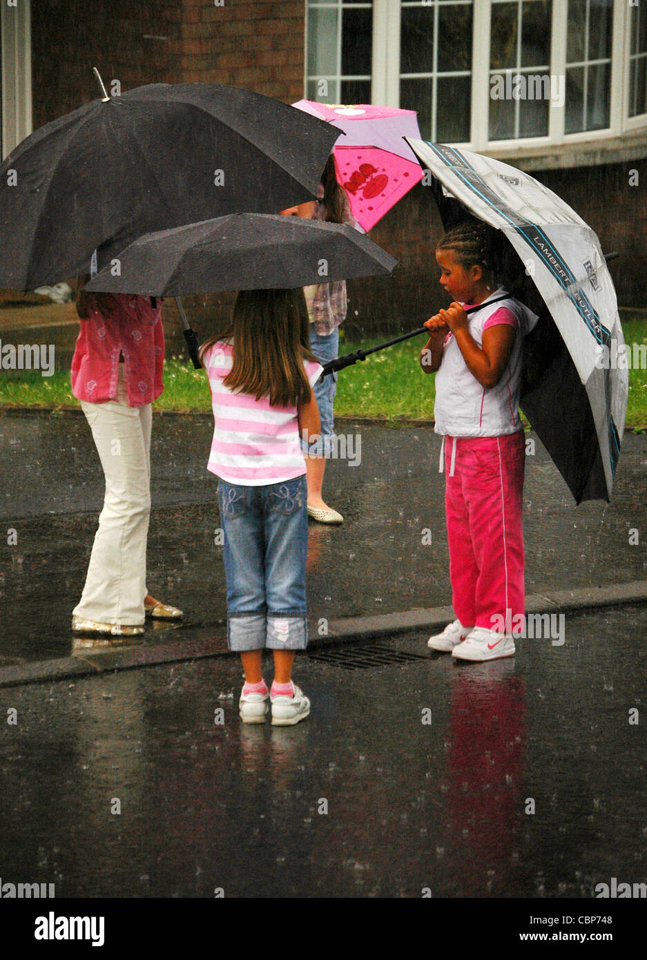Young girls holding umbrellas in rain hires stock photography and