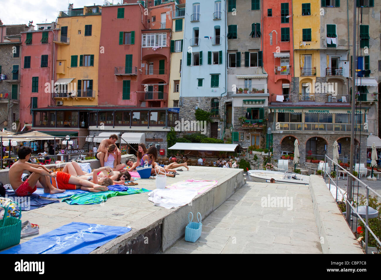 People taking a sunbath on the pier, harbour of fishing village Porto