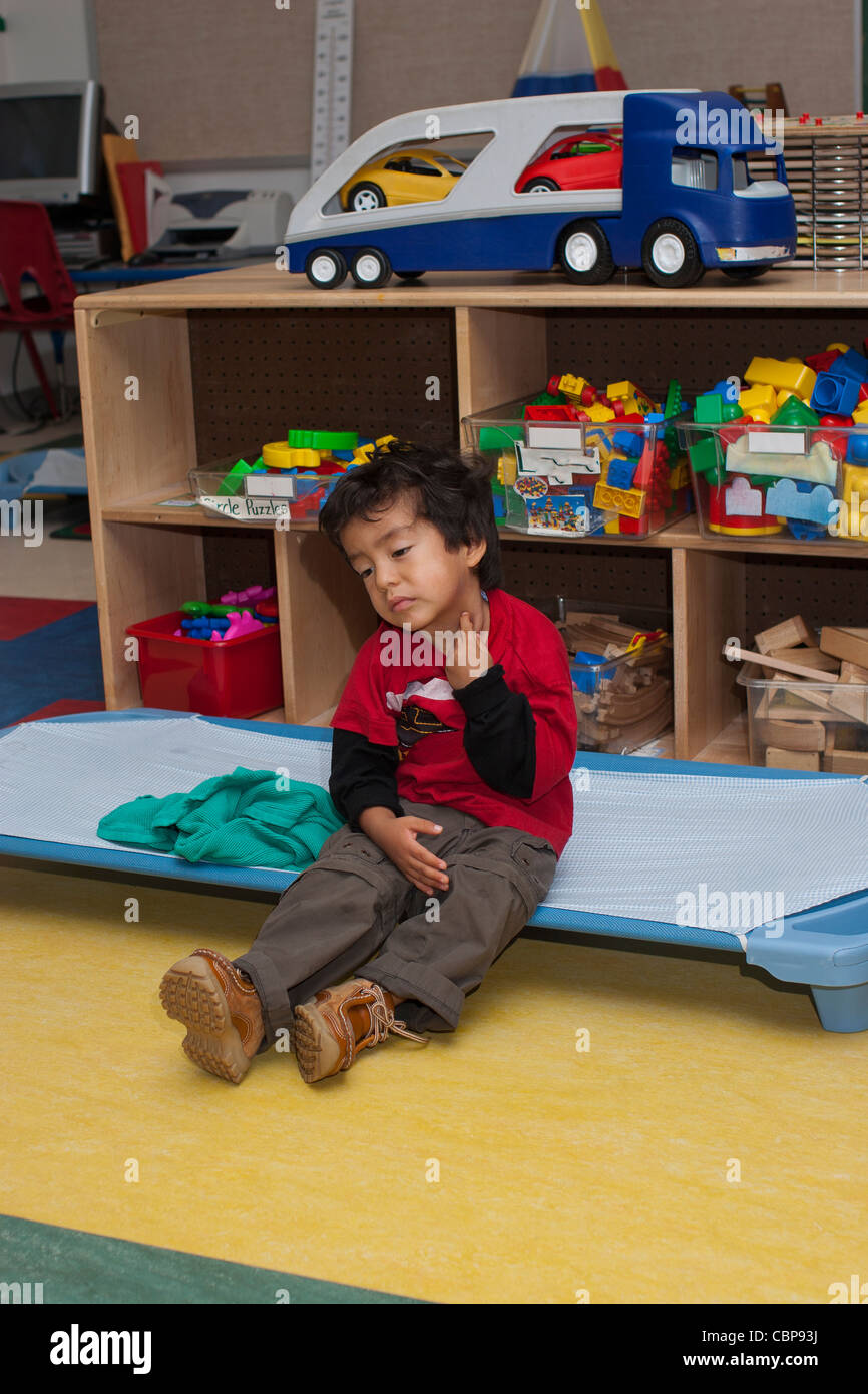 4 year old preschool boy waking up from a nap in the classroom during