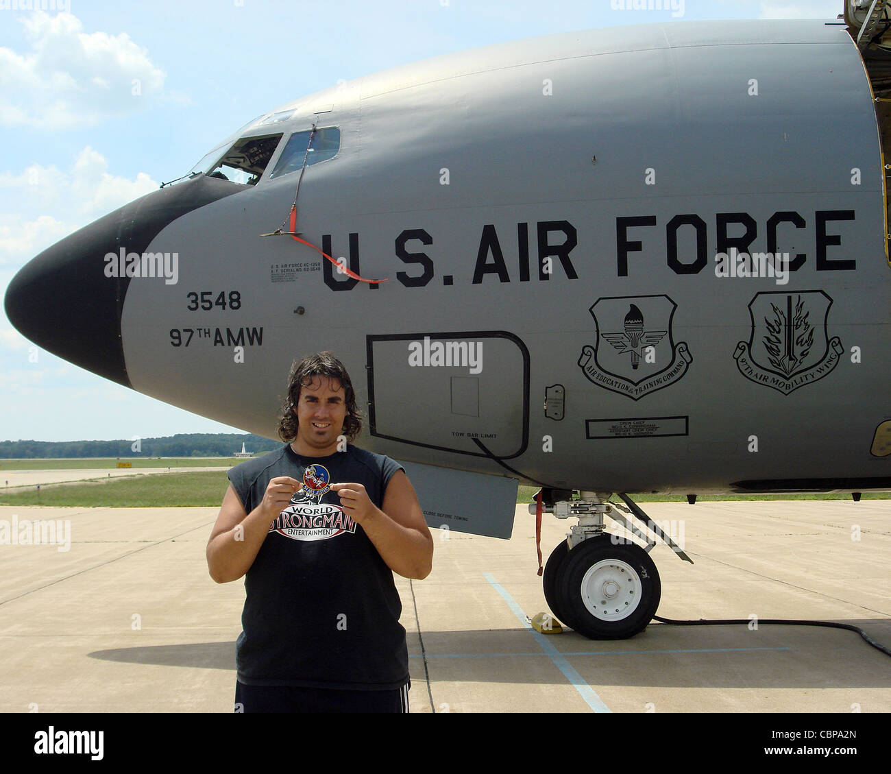 Strongman Mark Kirsch holds a 54th Air Refueling Squadron patch while standing in front of a KC-135 Stratotanker from Altus Air Force Base, Okla., July 1, 2011, during the Battle Creek Air Show and Balloon Festival in Battle Creek, Mich. Kirsch pulled the 140,000 pound aircraft five times during the air show. Stock Photo
