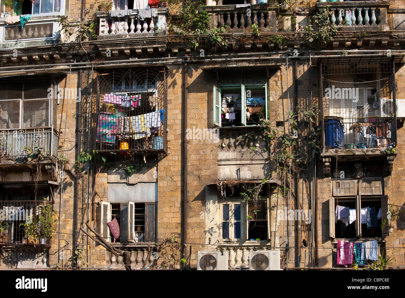 Tenement block traditional chawl housing scheme with air conditioning units and man in window in Parel area of Mumbai, India Stock Photo